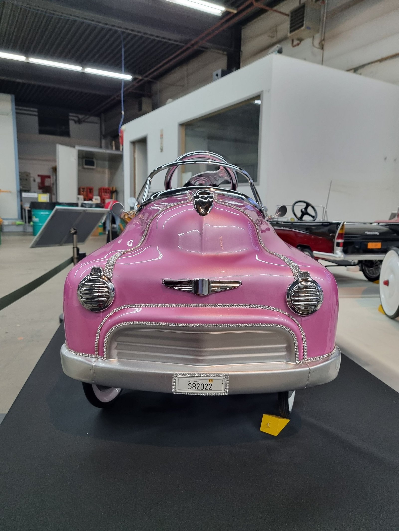 In einer Garage steht ein rosa Tretauto.